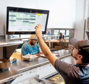 A man using a big screen kds at the order counter