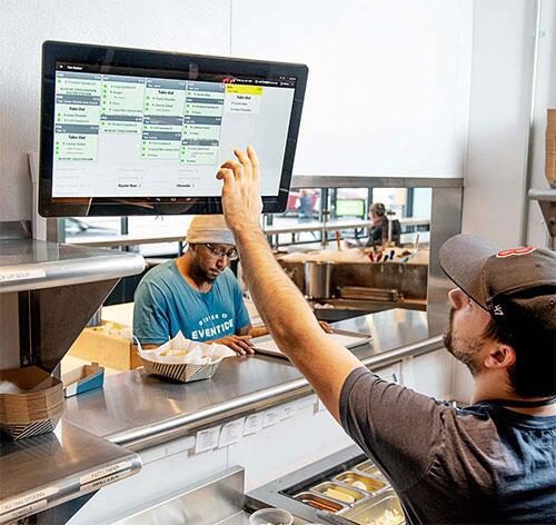 A man using a big screen kds at the order counter